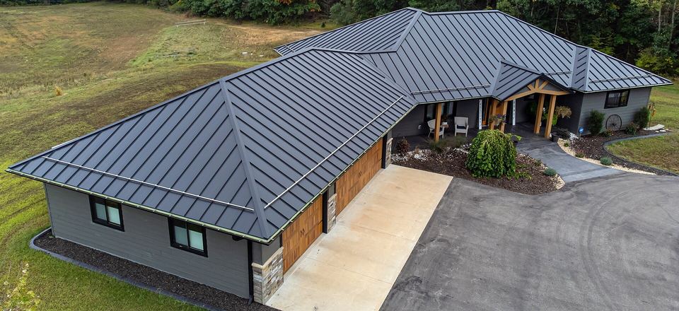 Aerial view of a ranch house with a dark gray standing-seam metal roof